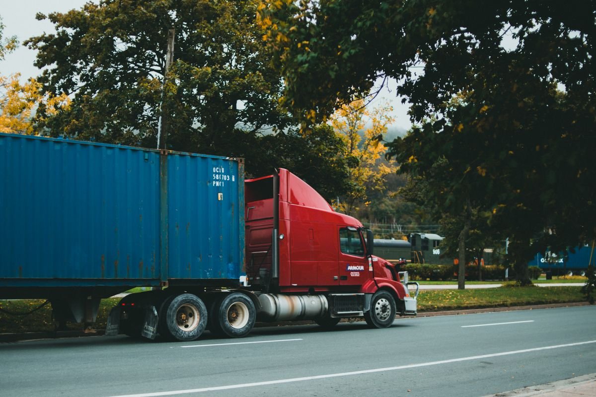 Camion transportant un conteneur sur une route — photographie d’illustration
